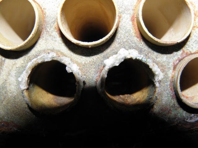 Detailopname van pijpuiteinden met golvende, weggesleten randen door erosie corrosie in een scheepsevaporator